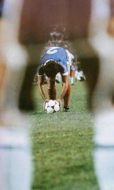 a man kneeling down with a soccer ball in front of him on the grass field