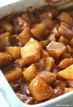 a casserole dish filled with cooked potatoes and brown gravy on the side