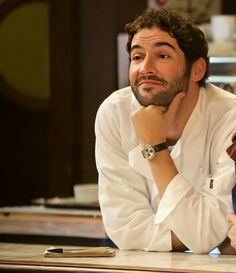 a man sitting at a table with his hand on his chin and looking off to the side