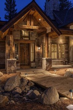 a house that is lit up at night with lights on the front porch and stone steps leading to it