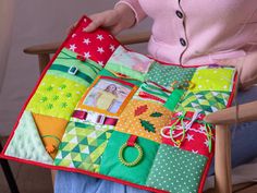 a woman sitting in a chair holding a colorful patchwork quilt