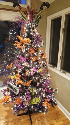 a decorated christmas tree in the corner of a room with lights and decorations on it