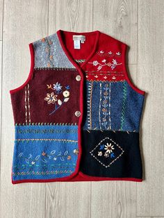 two vests with different colors and designs on them sitting on a wooden floor next to each other