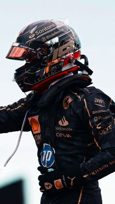 a man in a racing suit and helmet holding his hand out to the other side