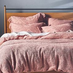 an unmade bed with pink sheets and pillows