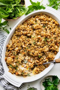 a white casserole dish filled with stuffing and garnished with parsley