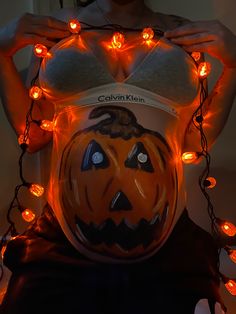 a woman is wearing a pumpkin costume with orange lights around her waist and chest, as if for halloween