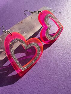 > hot pink and glitter acrylic heart shaped earrings are perfect for valentine's day or your next y2k look > a gift that sparkles * they would make a wonderful gift for someone who likes unique handmade jewelry * > the cut out hearts are laser engraved 1/8th inch thick acrylic with sterling silver ear wires > they are hypo-allergenic and nickel free  > the acrylic hearts are 1.75 inches wide and 1.72 inches long with a drop length of .5 inches  > feel free to message me if you would like to request a custom size > check my other listings for many other color options such as purple and iridescent  > find me on instagram @queen.beams for a firsthand look at how my items are made <3 Pink Glitter Earrings For Valentine's Day, Pink Heart Cut Earrings With Heart Charm, Valentine's Day Pink Glitter Earrings, Pink Heart Charm Earrings For Valentine's Day, Pink Glitter Heart Earrings For Party, Valentine's Day Heart Earrings With Heart Print, Valentine's Day Party Heart Earrings With Open Heart Shape, Pink Glitter Jewelry For Valentine's Day, Trendy Pink Double Heart Earrings