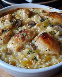 a white bowl filled with rice covered in chicken and mushroom sauce on top of a wooden table