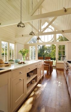 a large kitchen with wooden floors and white walls, has an island in the middle