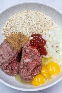 meat, eggs, and other ingredients in a bowl on a white counter top with a spoon