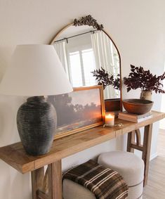 a table with a mirror, lamp and vase on it