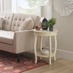 a white couch sitting next to a table on top of a rug in a living room