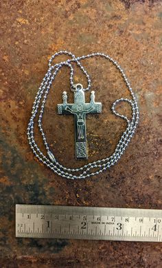 a cross is shown with a ruler on the ground next to it's chain