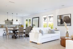 a living room filled with furniture next to a dining room table and kitchen area in the background