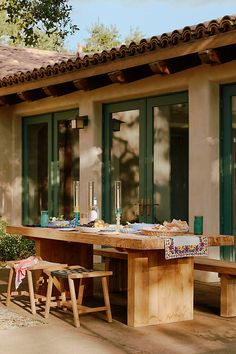 an outdoor dining area with wooden tables and green glass doors on the side of a house