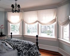 a bed sitting under two windows in a bedroom