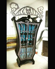 an ornate glass cabinet in the shape of a bookcase, with blue and black stained glass doors