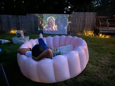 a man laying on top of a pink inflatable chair next to a projection screen