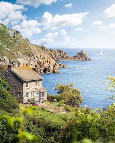 a house sitting on top of a lush green hillside next to the ocean