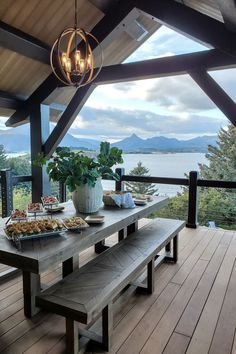 a table with food on it and some lights hanging from the ceiling over looking a body of water