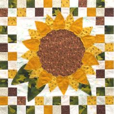 a sunflower on a checkered table cloth with green and yellow leaves in the center