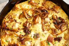 a casserole with onions and cheese in a black pan on a white table