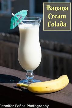 a banana sitting on top of a wooden table next to a glass filled with milk