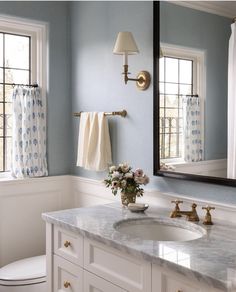 there is a bathroom with blue walls and white counter tops, along with a gold faucet