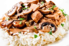 a white plate topped with rice covered in mushrooms and mushrooms on top of brown gravy