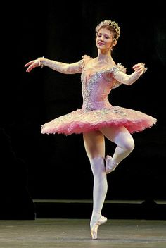 a ballerina in pink and white is performing on stage