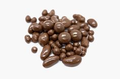 some chocolate beans are on a white surface and there is no image in the top right corner