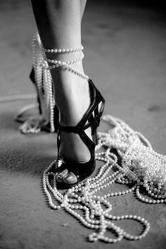 black and white photograph of woman's shoes with pearls on the ankle strap, high heeled sandals