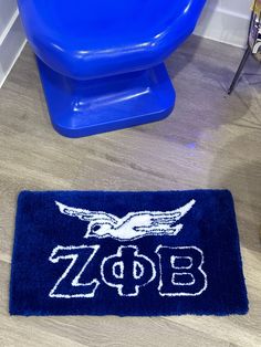 a blue toilet sitting next to a bathroom rug with the word zoo on it in white