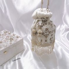 Elevate your bridal ensemble with our exquisite Ivory Bridal Wedding Day Potli Bag. Crafted from luxurious velvet fabric, adorned with intricate zardozi embroidery, this potli bag exudes elegance and opulence. The delicate beadwork adds a touch of glamour, while the beautiful log tassels at the bottom enhance its regal charm. Complete with a beaded latkan and a beaded strap, this potli bag is the perfect accessory to complement your bridal look, adding a timeless allure to your special day. Product Details: *Handmade with traditional Pakistani and Indian techniques *Spacious interior  *Measures 6 inches To explore additional styles, kindly visit our website at dulhansdiary.etsy.com. . . . . . . #Ivorypotlibag #handmadeclutch #bridalhandbag #weddingaccessories #ethnicbag #uniquegift #artisa Pink Wedding Outfit, Embroidery Shoes Diy, Bridal Pouch, Hand Embroidered Jewelry, Zardozi Embroidery, Beaded Strap, Bridal Handbags, Vegan Leather Tote Bag, Bead Crochet Patterns