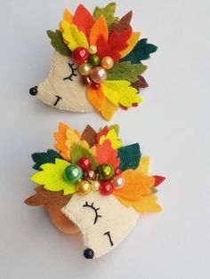 two felt hedges decorated with colorful leaves and pearls, one has a face on it's head