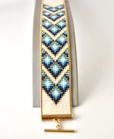 a beaded bracelet on display with a gold bar in the middle and blue beads around it