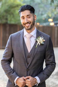 a man in a suit and tie smiles at the camera with his hands in his pockets