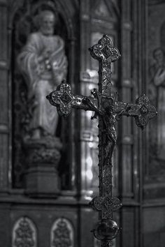 an ornate cross in front of a statue