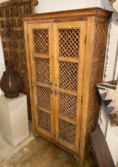 a wooden cabinet sitting next to a white vase