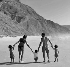 a black and white photo of a family walking on the beach