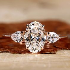 Close-up of an oval diamond ring in a rose gold setting Oval And Pear Engagement Ring, Oval With Side Stones, Oval Three Stone Engagement Ring, Three Stone Oval Engagement Ring, Fall Guy, Moissanite Vs Diamond, Colored Diamond Rings, Oval Engagement Ring, Three Stone Diamond Ring