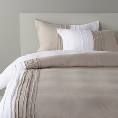 an image of a bed with white and beige sheets