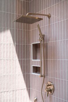 a shower head and hand held shower faucet in a pink tiled bathroom area