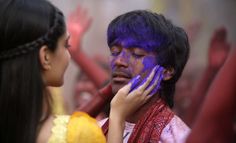 a man with purple paint on his face talking to a woman in front of him