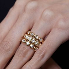 a woman's hand with gold and diamond rings on her fingers, holding onto the ring