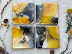 four yellow and black coasters sitting on top of a white table next to pine cones