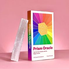 the prism oracle book is next to it's box on a pink tablecloth