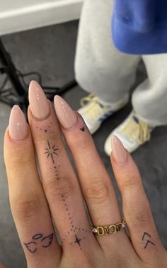 a woman's hand with tattoos on it and a gold band around her finger