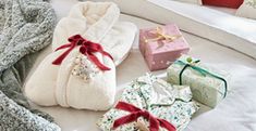 several wrapped presents are sitting on the bed next to pillows and blankets, along with two gift bags